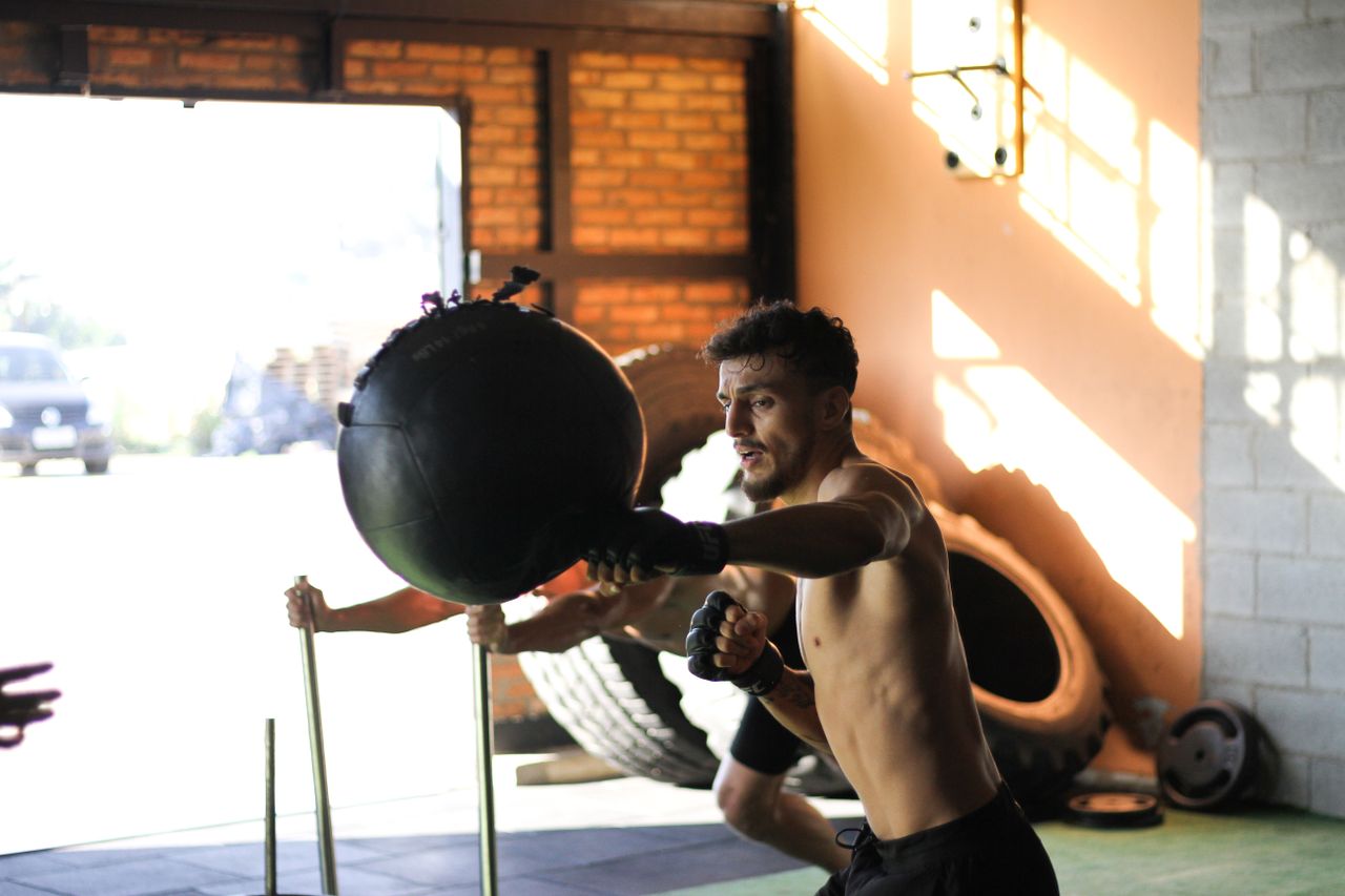 why-choose-us-02 Athletic man practicing punching exercises with a bag indoors, demonstrating strength and focus.
