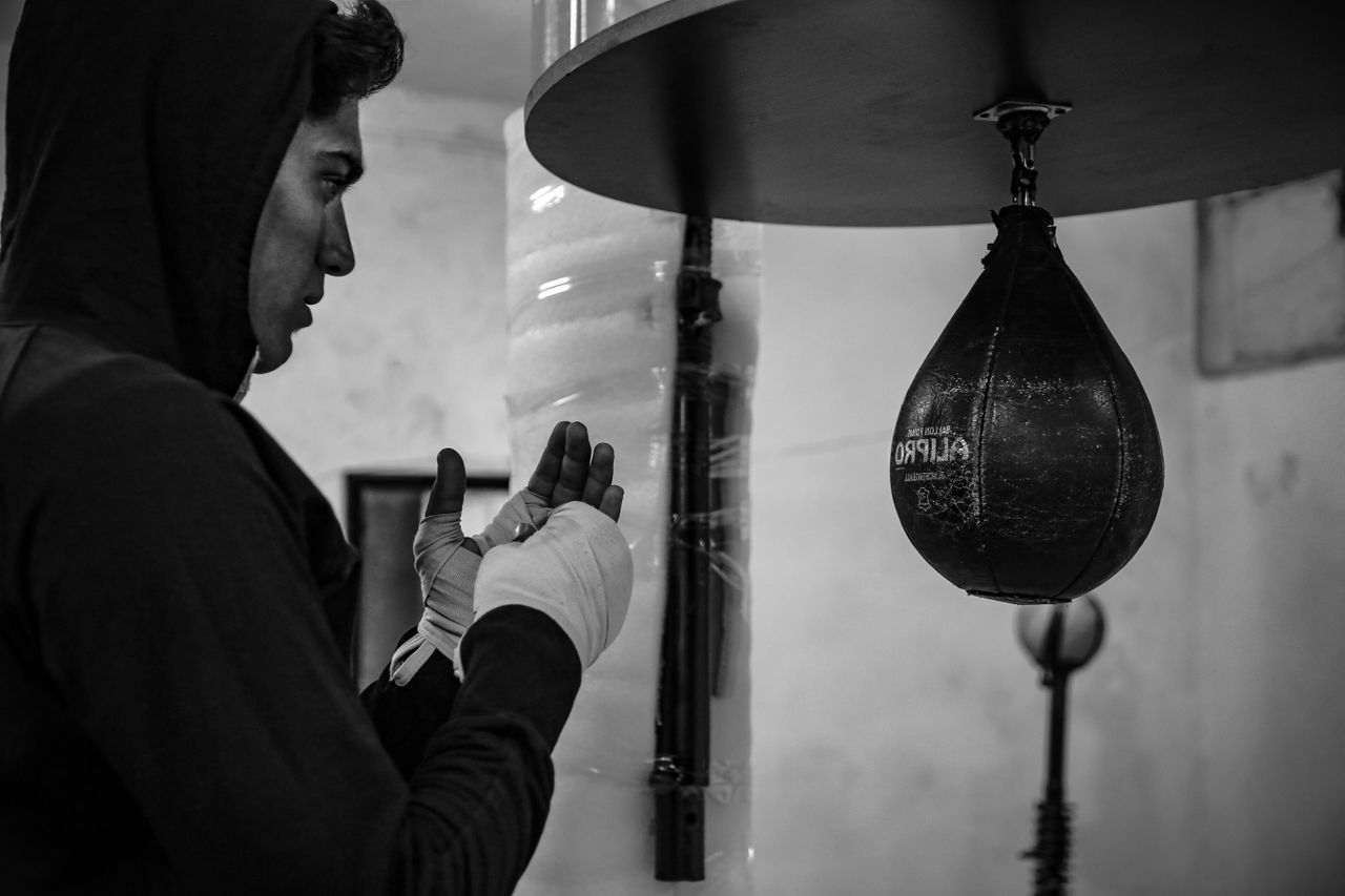 our-story-02 A focused boxer trains with a speed bag in an indoor gym setting.