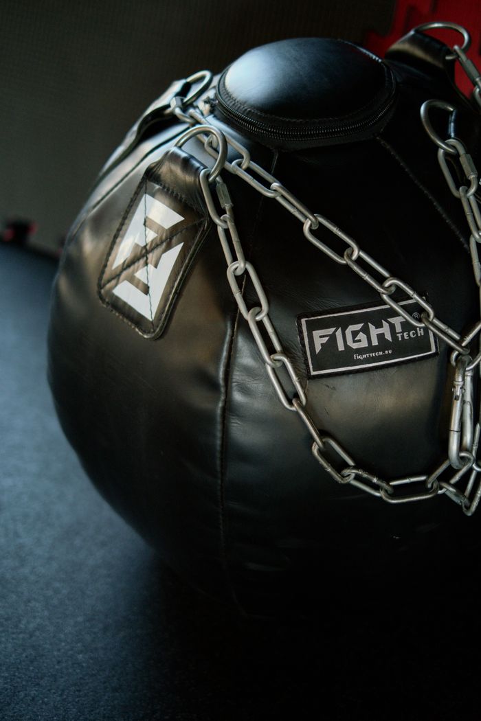Close-up of a black punching bag with chains in a gym setting, ideal for boxing and training.