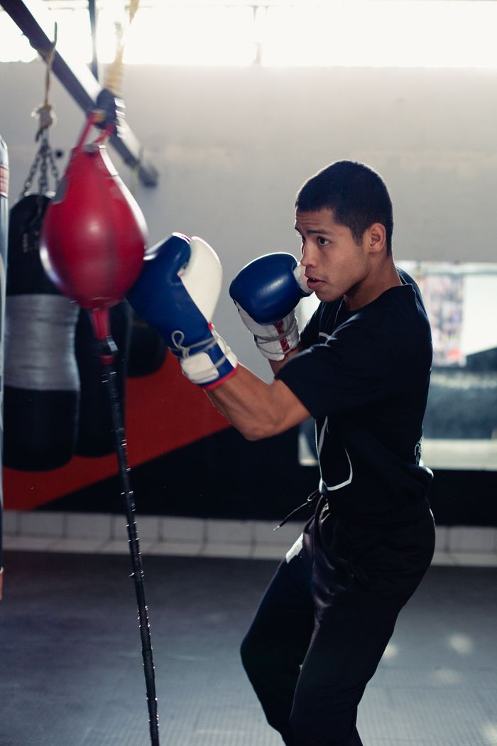 why-choose-us-01 A young male boxer practicing in a gym with focus and determination.